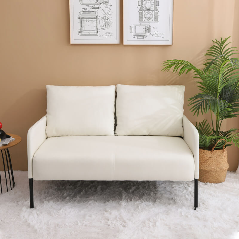 Front view of beige linen loveseat with slim metal legs in a small living room setting