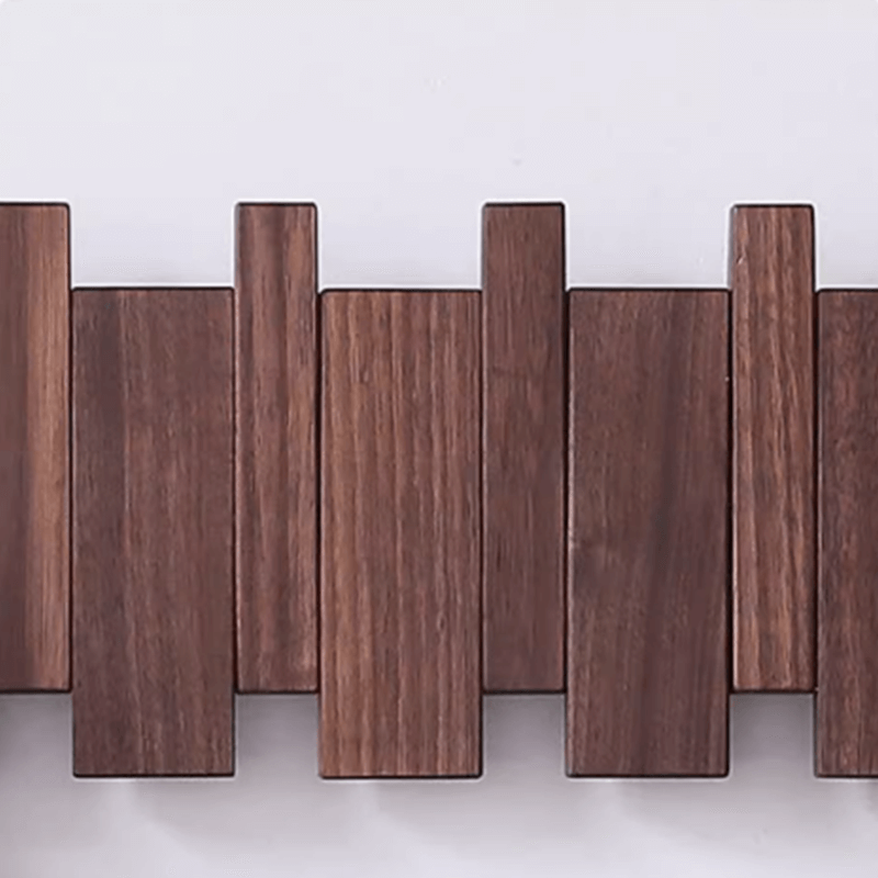 Black walnut wall-mounted coat rack in a stylish entryway, neatly organized.