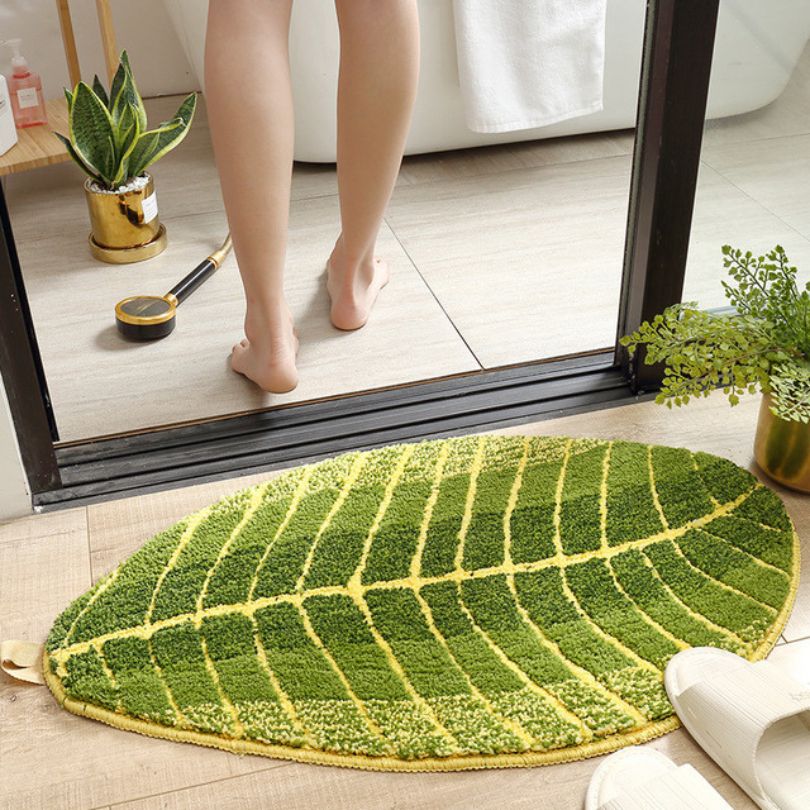 Soft green non-slip bathroom mat placed in front of a bathtub, enhancing the bohemian decor of the room.