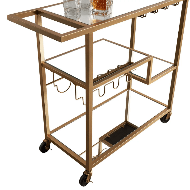 Close-up view of the shelves on the gold mirror bar cart, displaying wine and glasses.