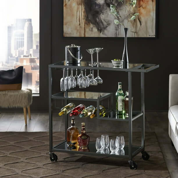 Close-up view of the shelves on the gold mirror bar cart, displaying wine and glasses.