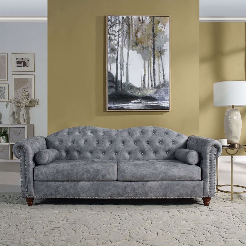 Elegant grey Chesterfield 3-seater button tufted sofa showcasing nailhead trim detail in a stylish living room setting.
