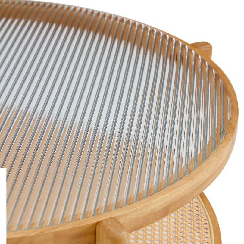 Modern circular glass coffee table with a rattan base, showcasing its elegant design.