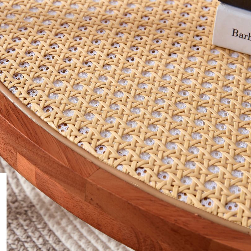 Chic circular teak glass coffee table showcasing rattan details in a modern living room.