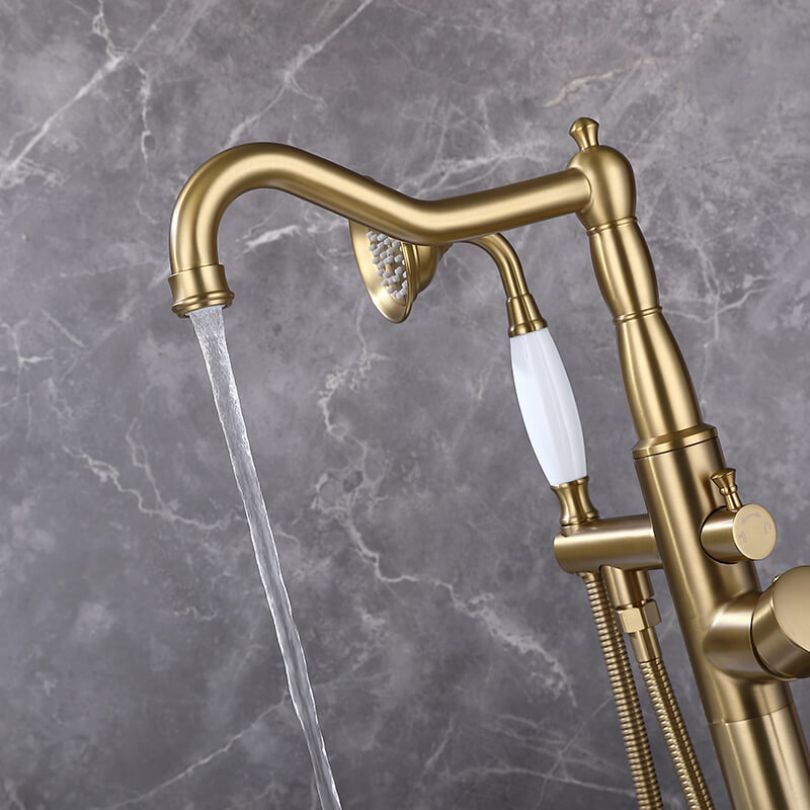 Elegant brushed gold freestanding faucet with handheld shower from the side view.
