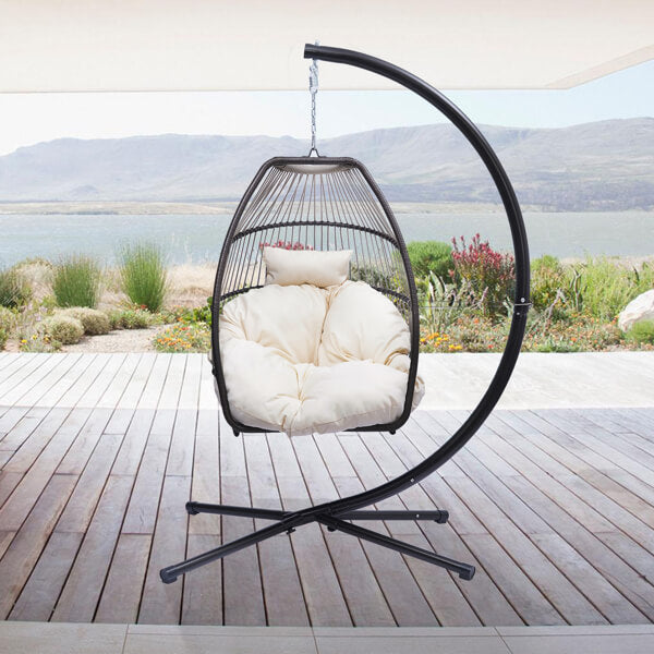 Trendy rattan swing hammock chair in a garden setting with blue cushion