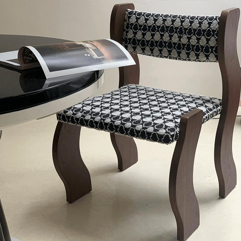 Stylish wavy frame dining chair with cushion in a modern dining room setting.