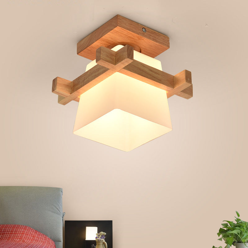 Close-up of wooden light fixture showing engraved detailing and frosted glass shade