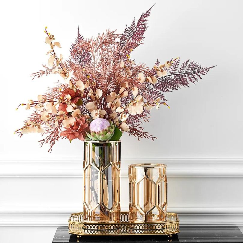 Elegant golden accent vase displayed on a dining table with flowers.