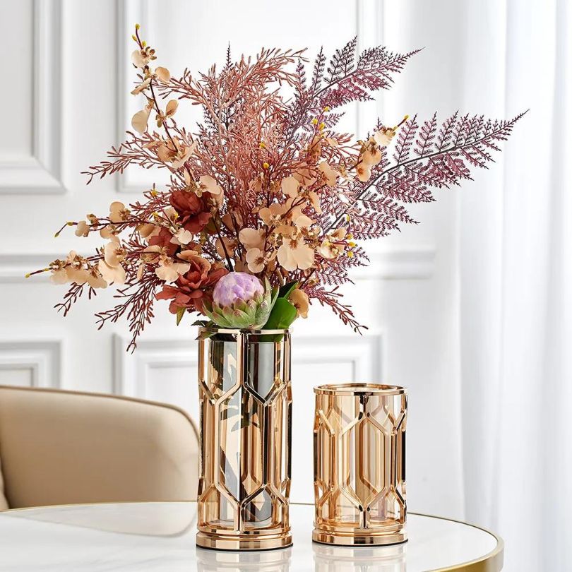 Elegant golden accent vase displayed on a dining table with flowers.