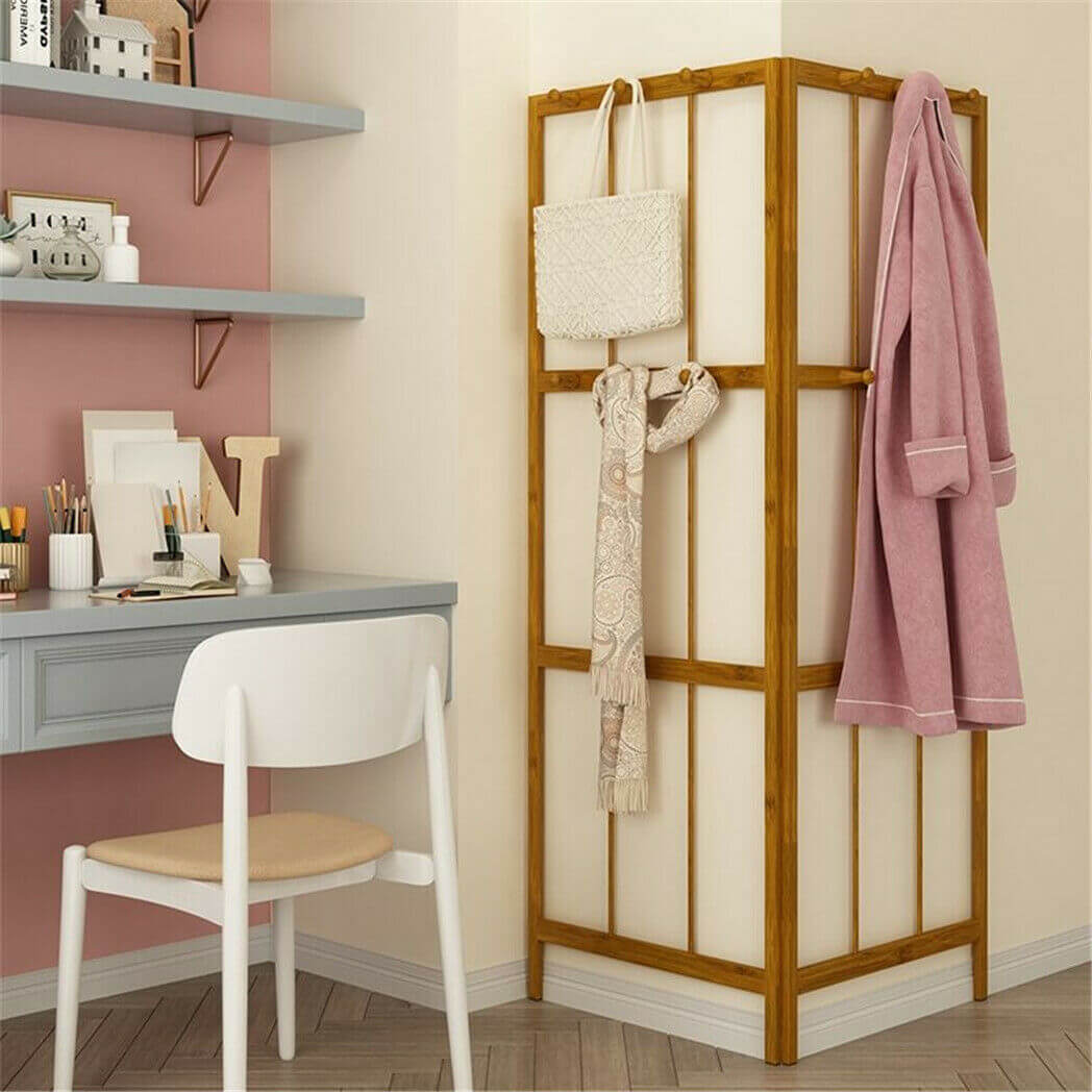 Folding bamboo coat stand placed in a corner, demonstrating its space-saving benefits.
