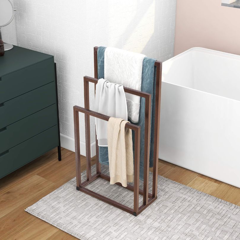 Freestanding towel holder in a modern bathroom setting, holding towels.
