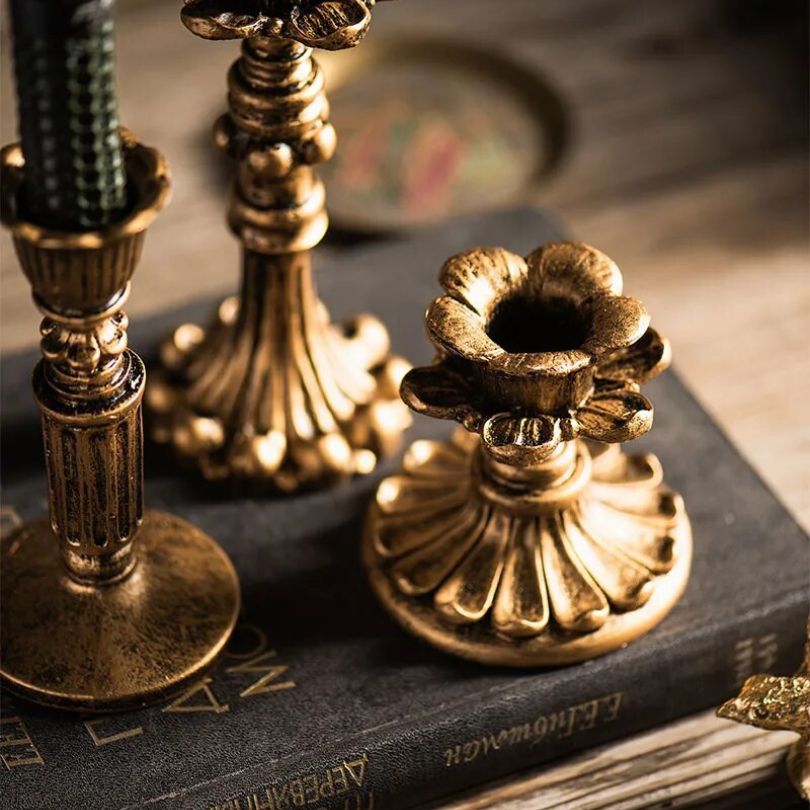 Multiple sizes of rustic gold candle holders arranged on a tabletop.