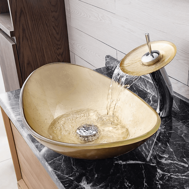 Gold ingot tempered glass vessel sink with waterfall faucet, showcasing its elegant design and smooth surface.