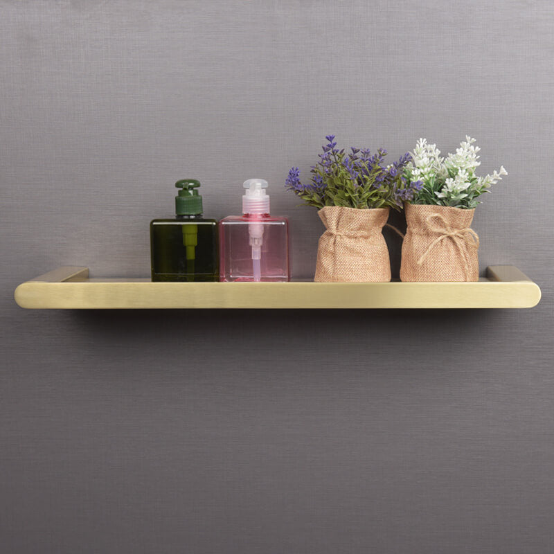 Elegant gold floating shelf showcasing a modern bathroom setup with toiletries displayed.