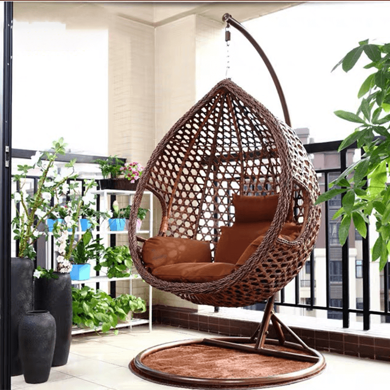 a person relaxing in the hanging rattan swing chair, enjoying a sunny patio