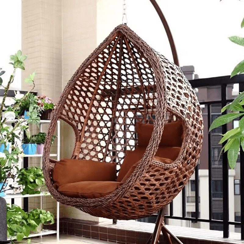 hanging rattan swing chair in a garden setting with lush greenery