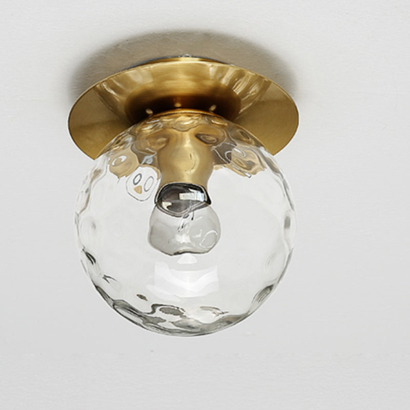 Close-up view of the mouth-blown glass sphere in the elegant gold ceiling light, highlighting its exquisite craftsmanship.