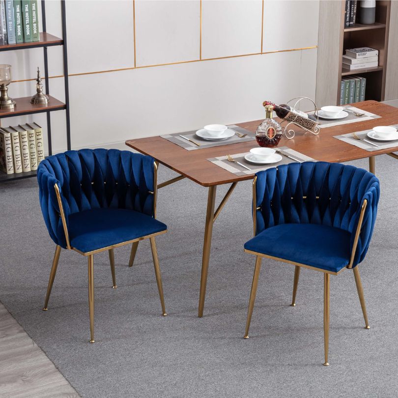 Close-up of the luxurious blue velvet fabric and golden legs of the dining chair.