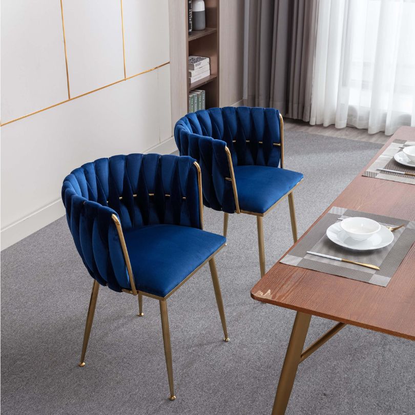 Close-up of the luxurious blue velvet fabric and golden legs of the dining chair.