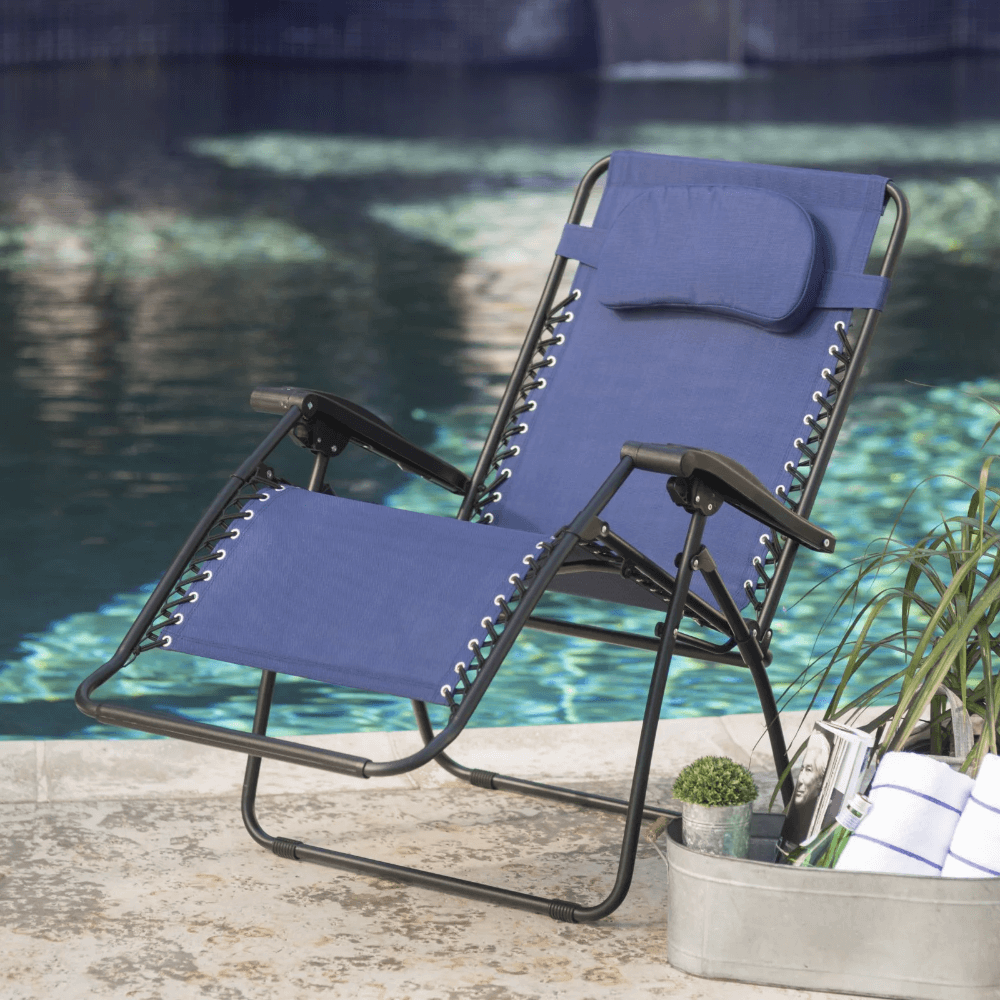 Side view of Caravan Comfort Blue Folding Outdoor Chair set up in a backyard.