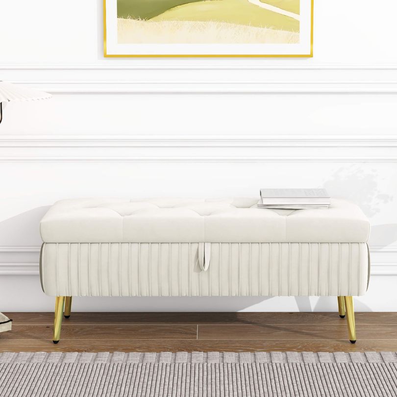 Front view of modern beige storage ottoman with golden legs in a stylish entryway.