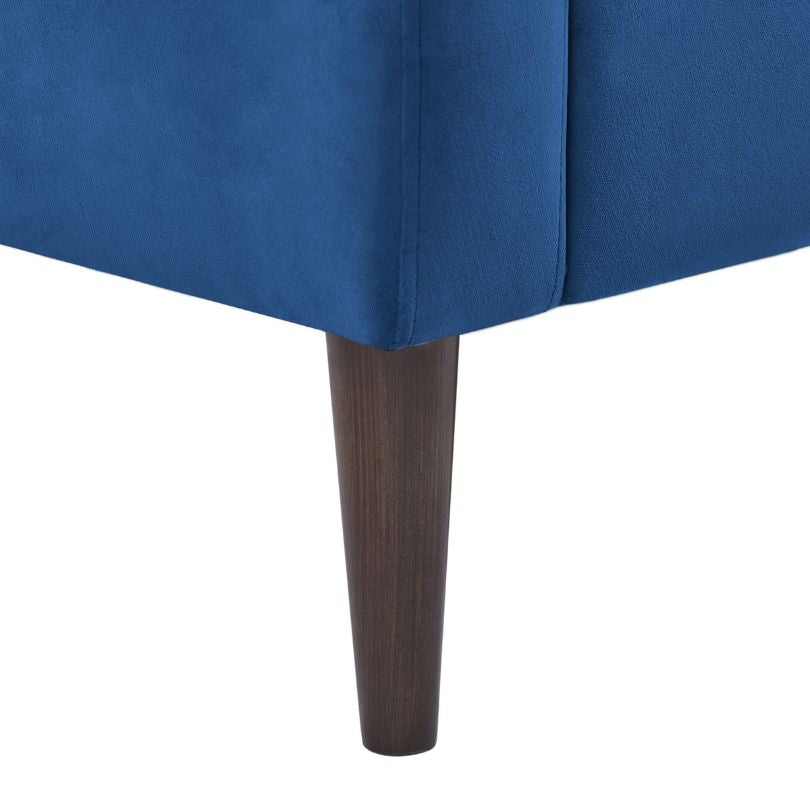 Front view of the modern blue accent chair in a stylish living room setting, highlighting its tufted details.