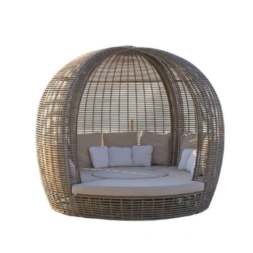 Elegant round rattan poolside daybed in a sunny garden setting, showcasing its sleek design and canopy.