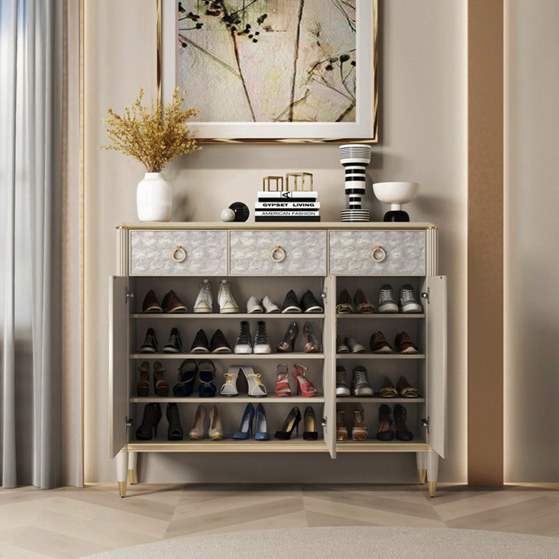 Elegant off-white shoe storage cabinet with doors, showing a side view in a bright entryway.