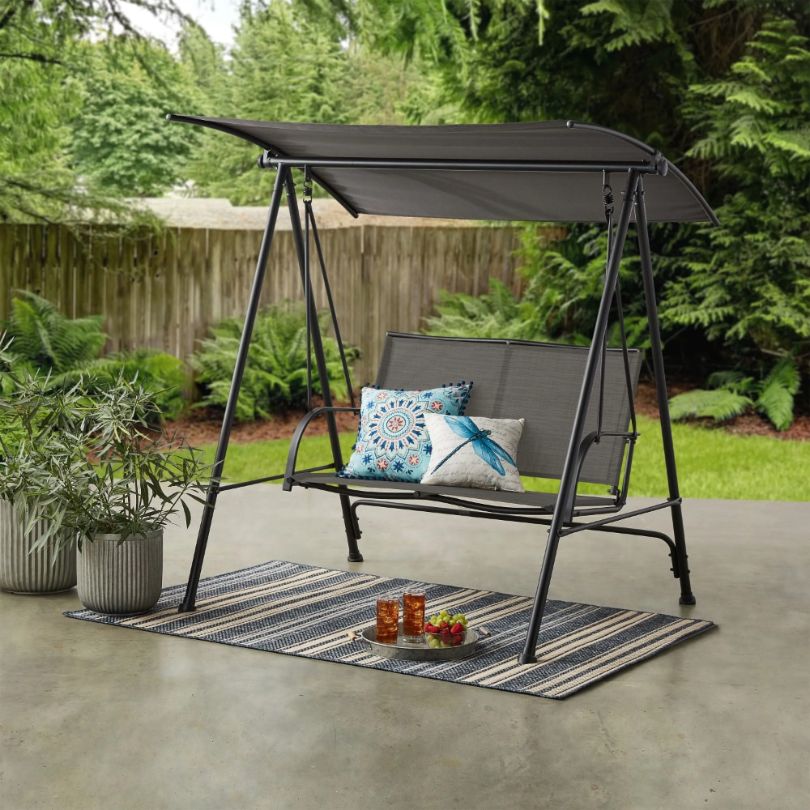 Side view of contemporary canopy swing chair for two in patio setting.