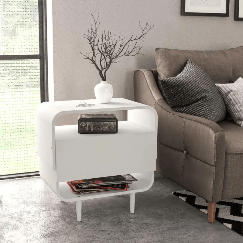 Elegant white nightstand with lamp and decor items on top in a beautifully styled bedroom.
