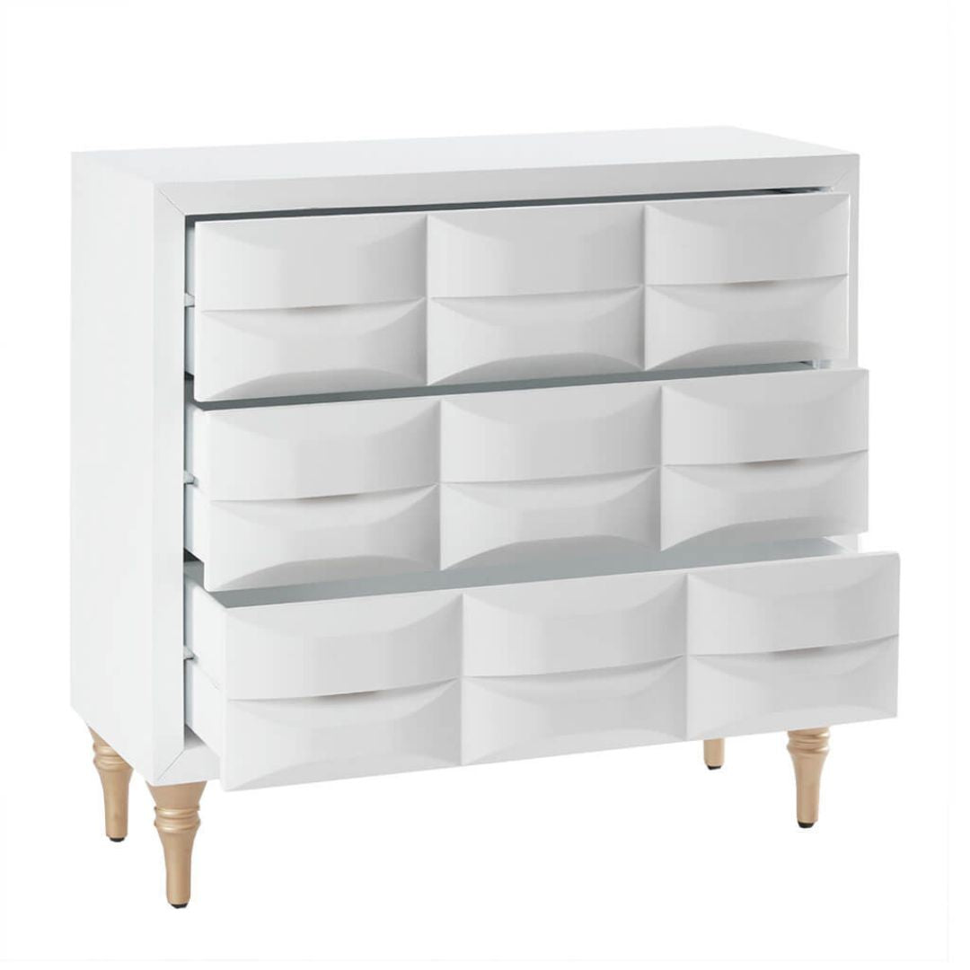 Angled front view of modern chest with white gloss finish and gold metal legs, showing all 3 drawers