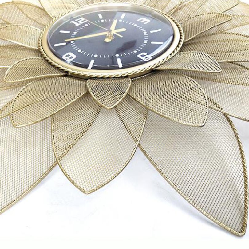 Sophisticated view of the gold wrought iron wall clock on a white wall.