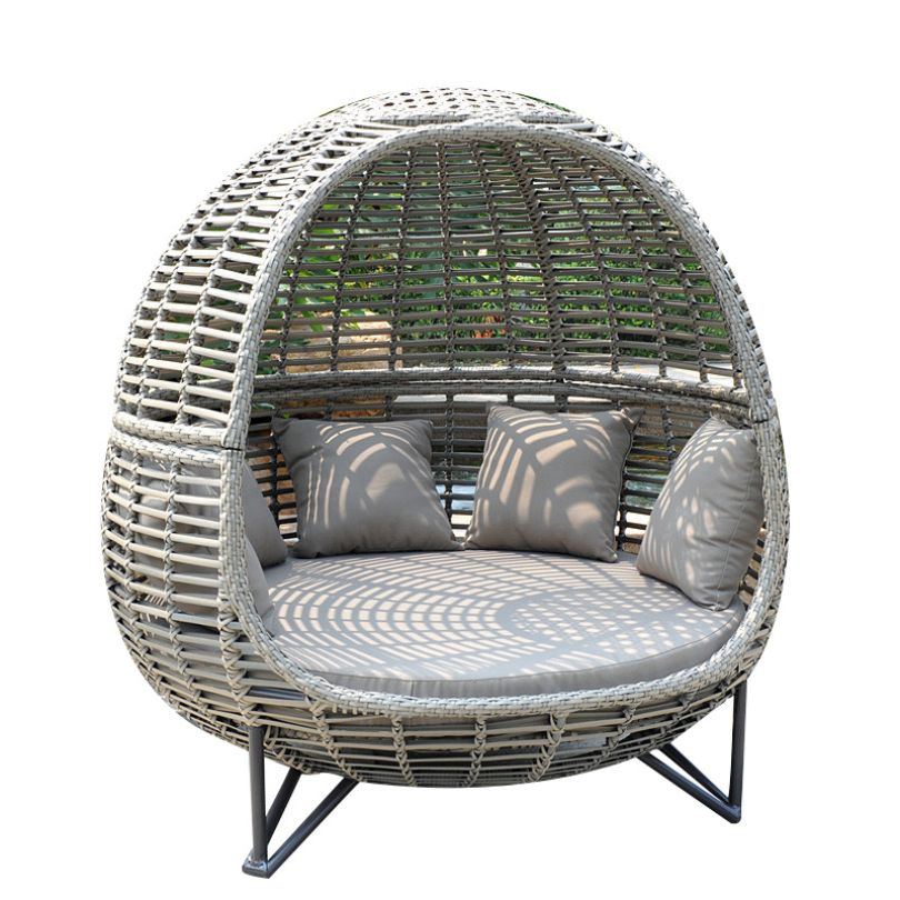The Nordic rattan daybed in a sunny garden setting, highlighting its stylish shape and durability.