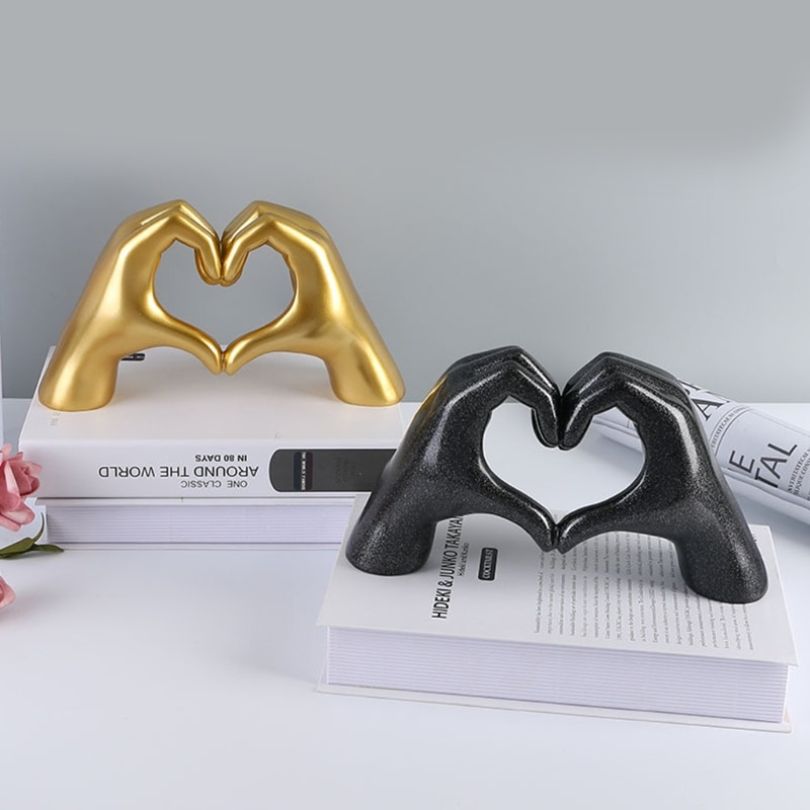 Golden Heart Gesture Sculpture displayed on a modern shelf, highlighting its intricate details.