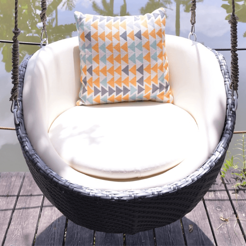 Side angle of the hanging rattan rocking chair in a garden, showing sturdy construction