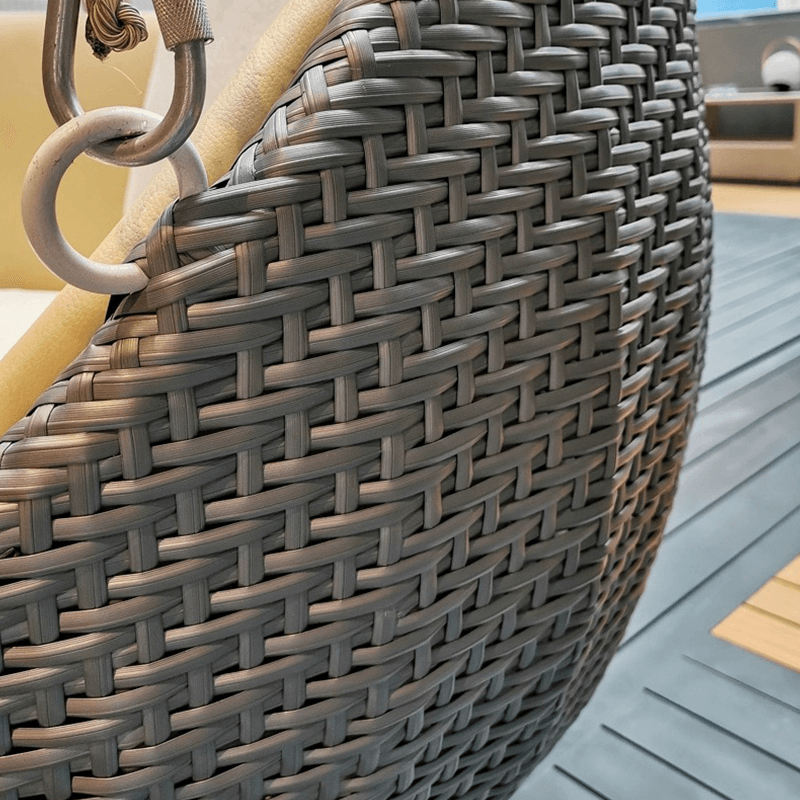 View of the comfortable rattan swing rocking chair on a porch, ideal for outdoor relaxation