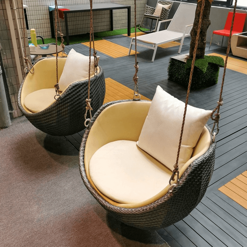 View of the comfortable rattan swing rocking chair on a porch, ideal for outdoor relaxation