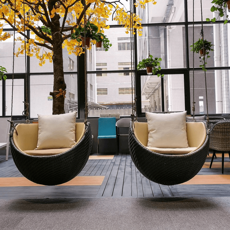 Close-up view of luxury rattan swing rocking chair on a patio with a cozy cushion