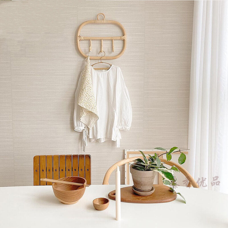 Elegant rattan coat hanger with three decorative hooks against a modern wall.