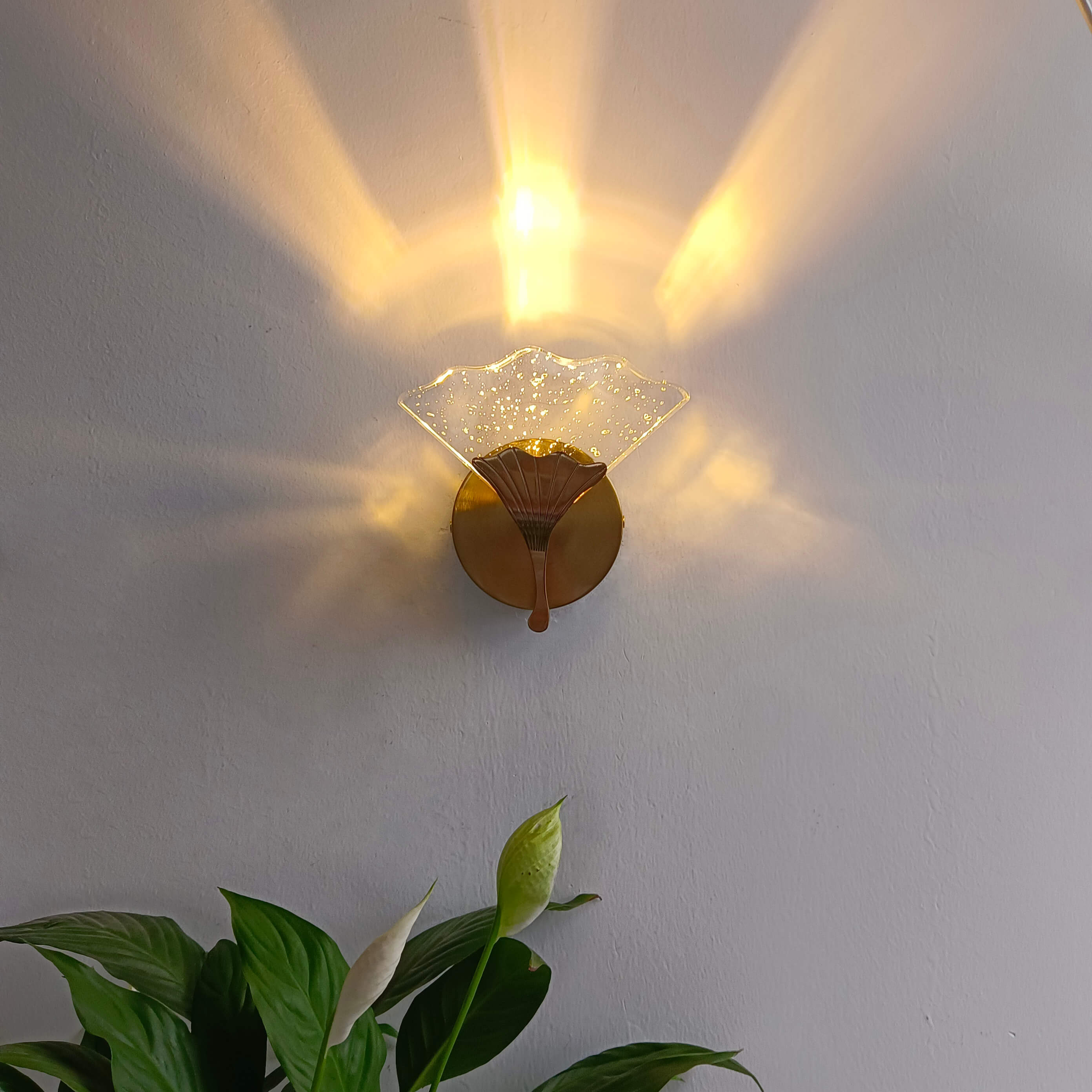 The elegant ginkgo leaf wall sconce mounted in a cozy entryway, providing ambient lighting.