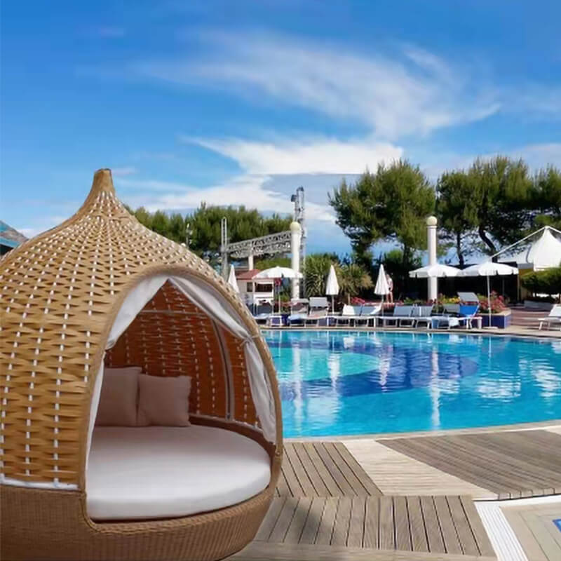 Rattan birdcage daybed sofa in a sunny garden, showcasing its elegant design.