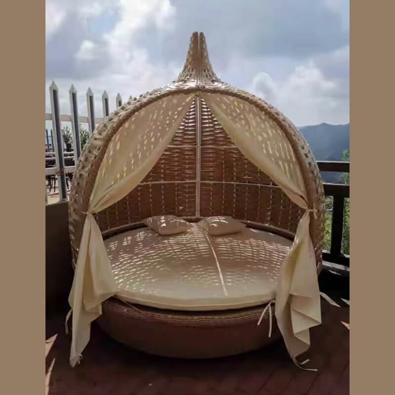 Rattan birdcage daybed sofa in a sunny garden, showcasing its elegant design.
