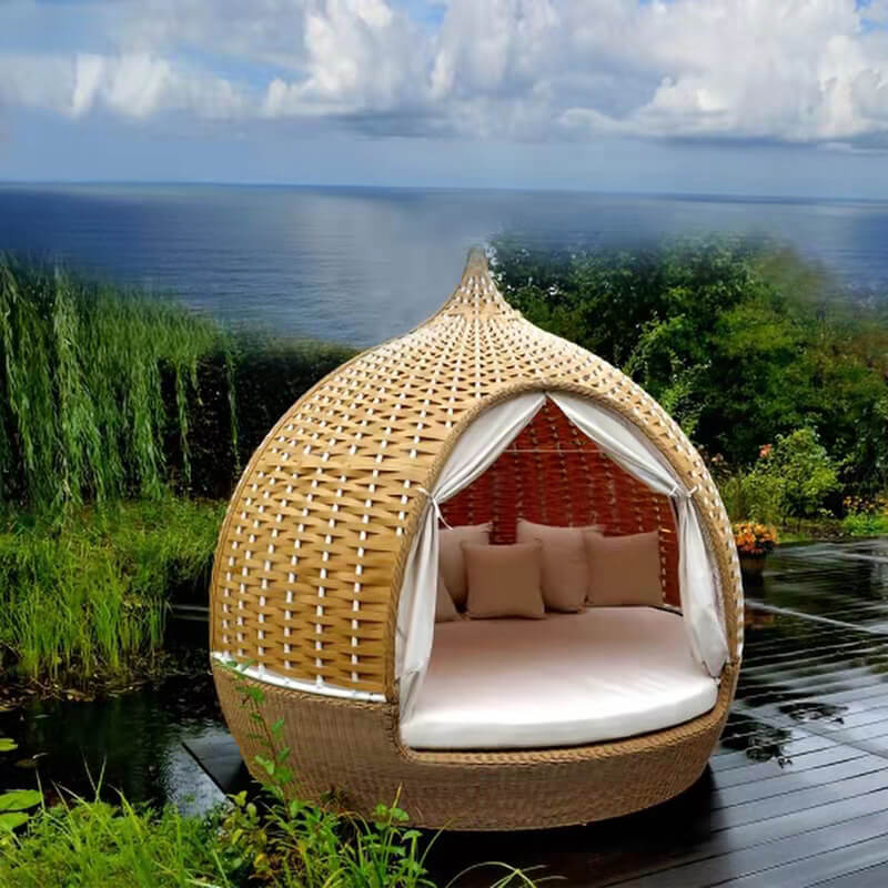 Rattan birdcage daybed sofa in a sunny garden, showcasing its elegant design.