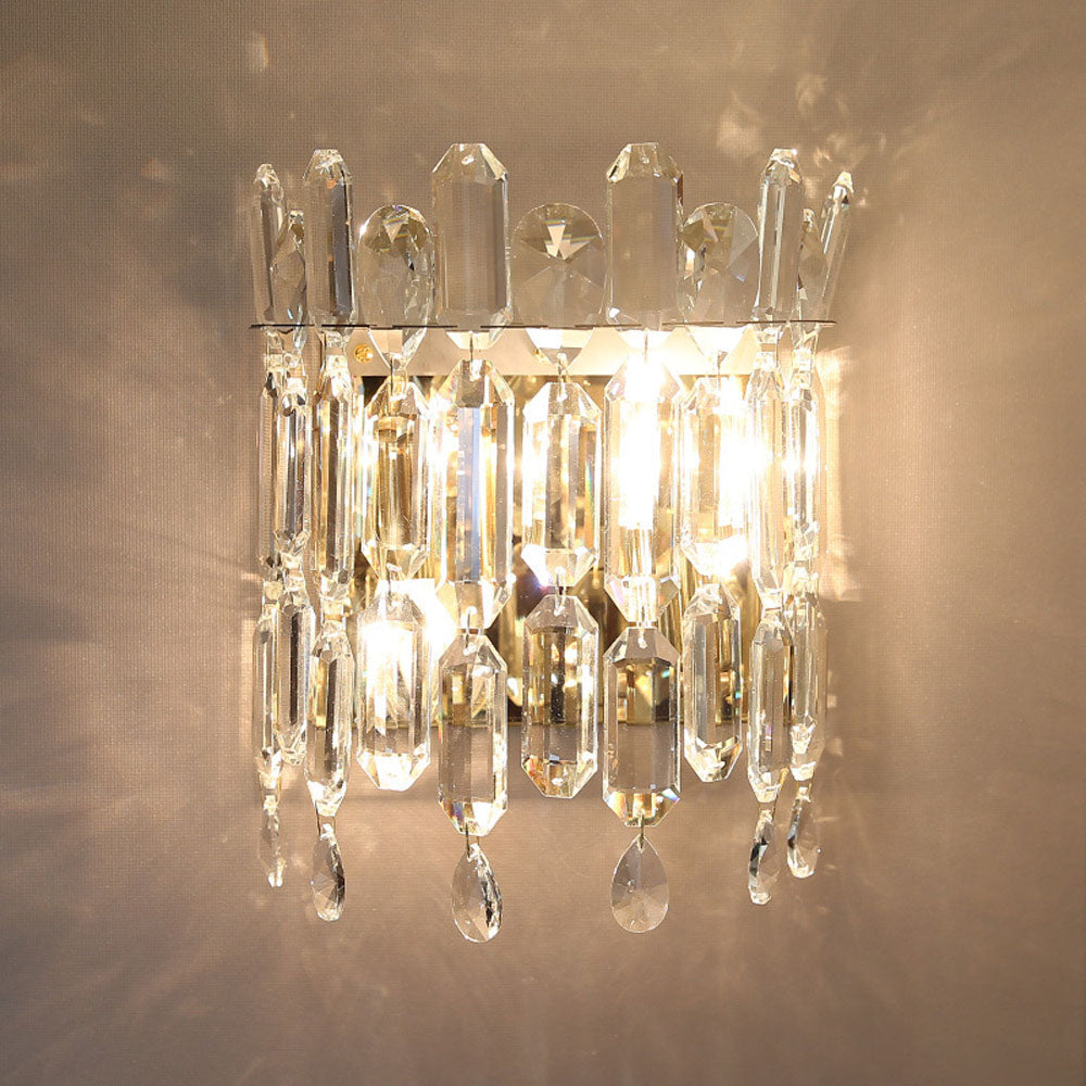 Gold crystal wall lamp in a cozy bedroom setting, illuminating the space beautifully.