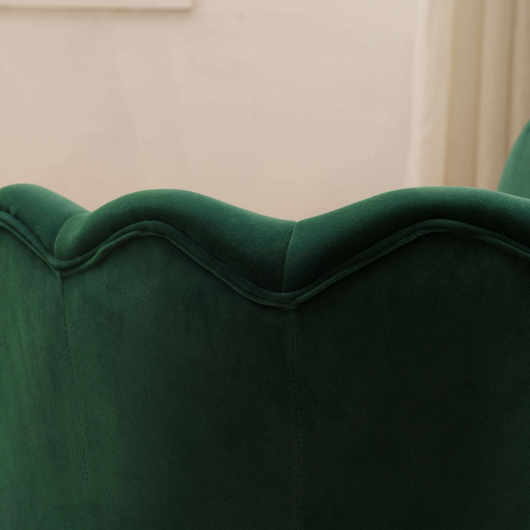 Side view of the dark green velvet accent chair showcasing its gold legs.