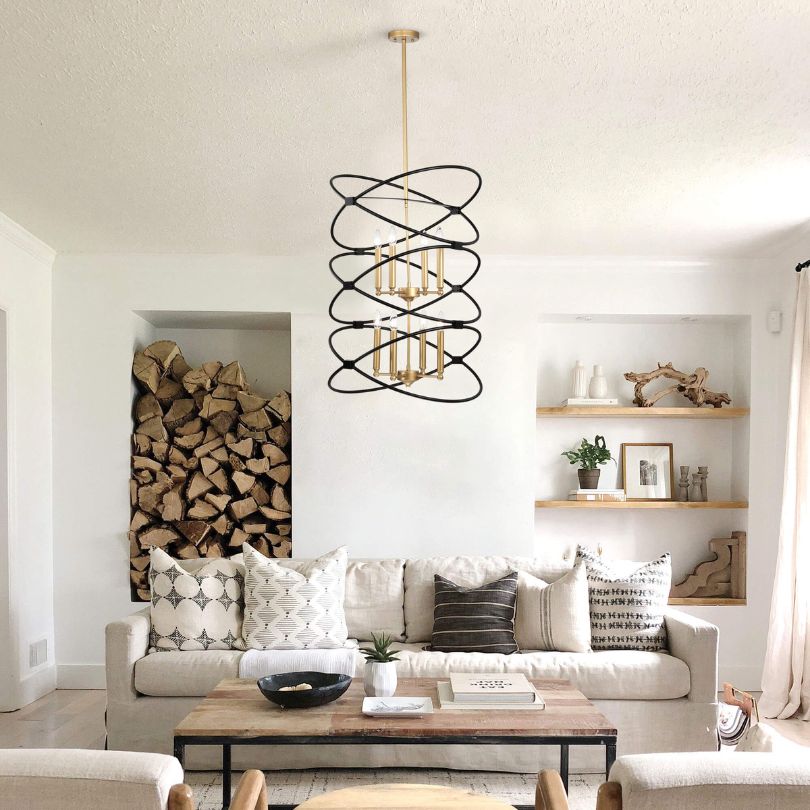 Angled view of the Marlowe chandelier hanging in a high-ceiling living room, showing matte black and gold finish.
