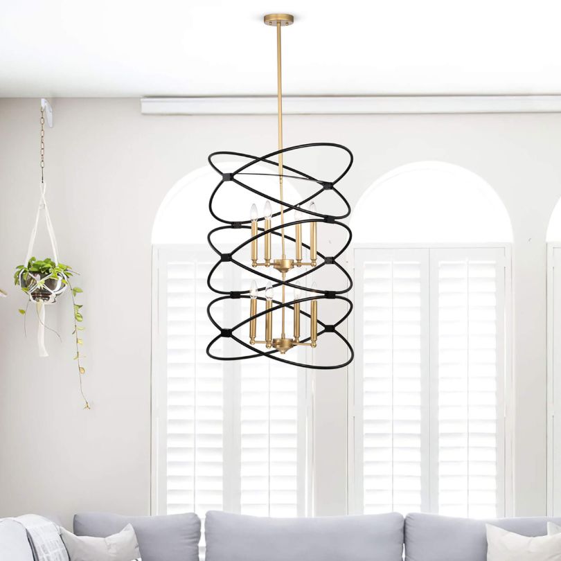 Angled view of the Marlowe chandelier hanging in a high-ceiling living room, showing matte black and gold finish.