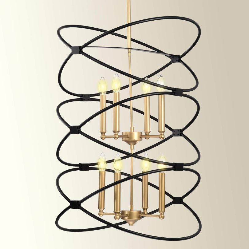 Angled view of the Marlowe chandelier hanging in a high-ceiling living room, showing matte black and gold finish.