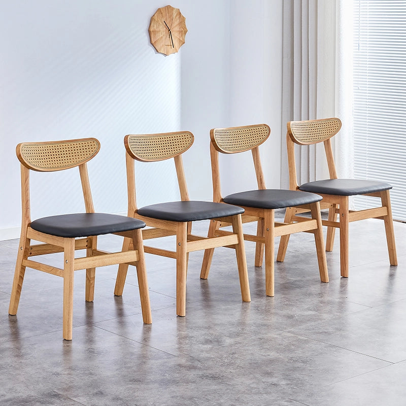 Elegant set of 4 upholstered dining chairs with curved backrest in a dining room setting.